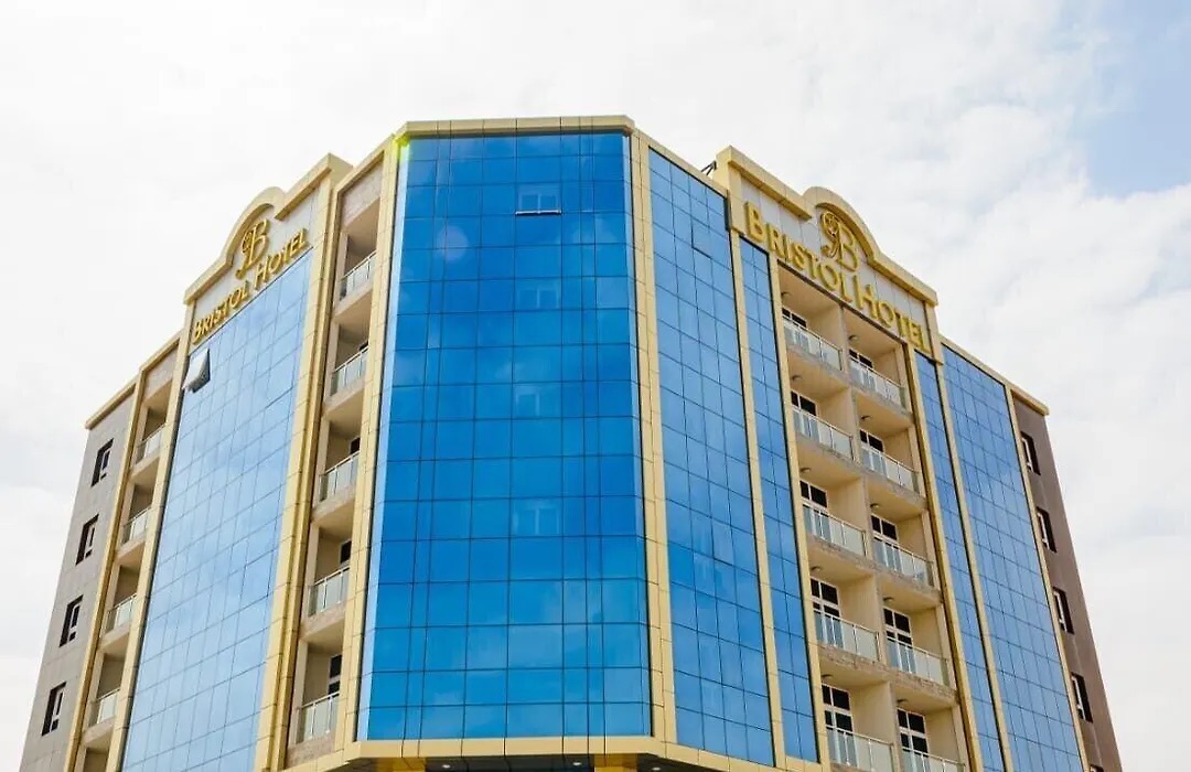 Bristol Hotel Salalah by day: a tall blue glass building with gold trim