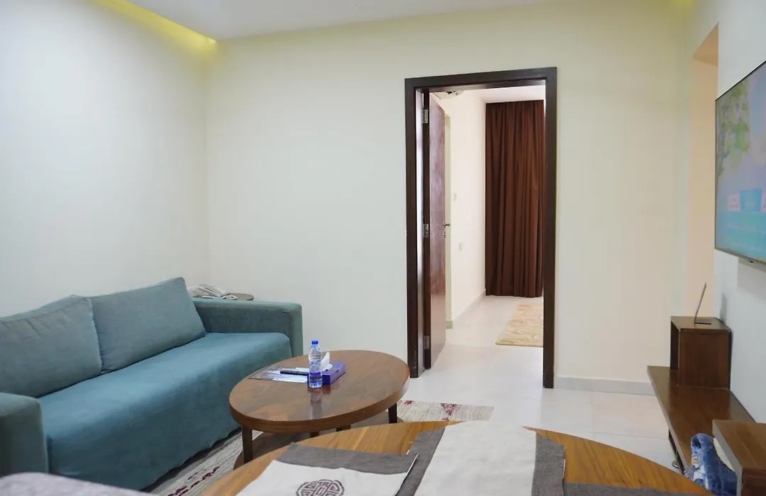 Suite living room with a teal sofa, coffee table and the door to the bedroom